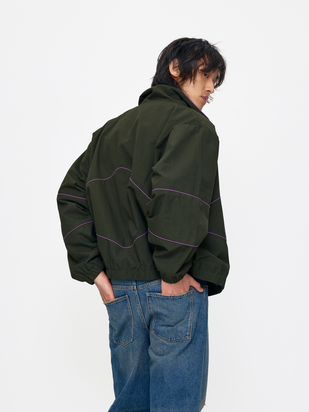 Person wearing a green jacket with purple accents on a white background