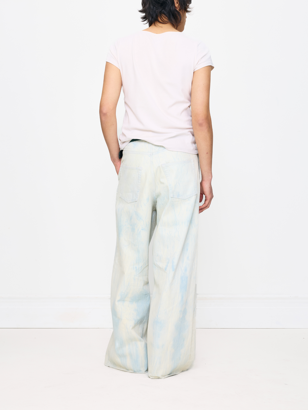 Person wearing light-colored tie-dye pants and a pink shirt on a white background