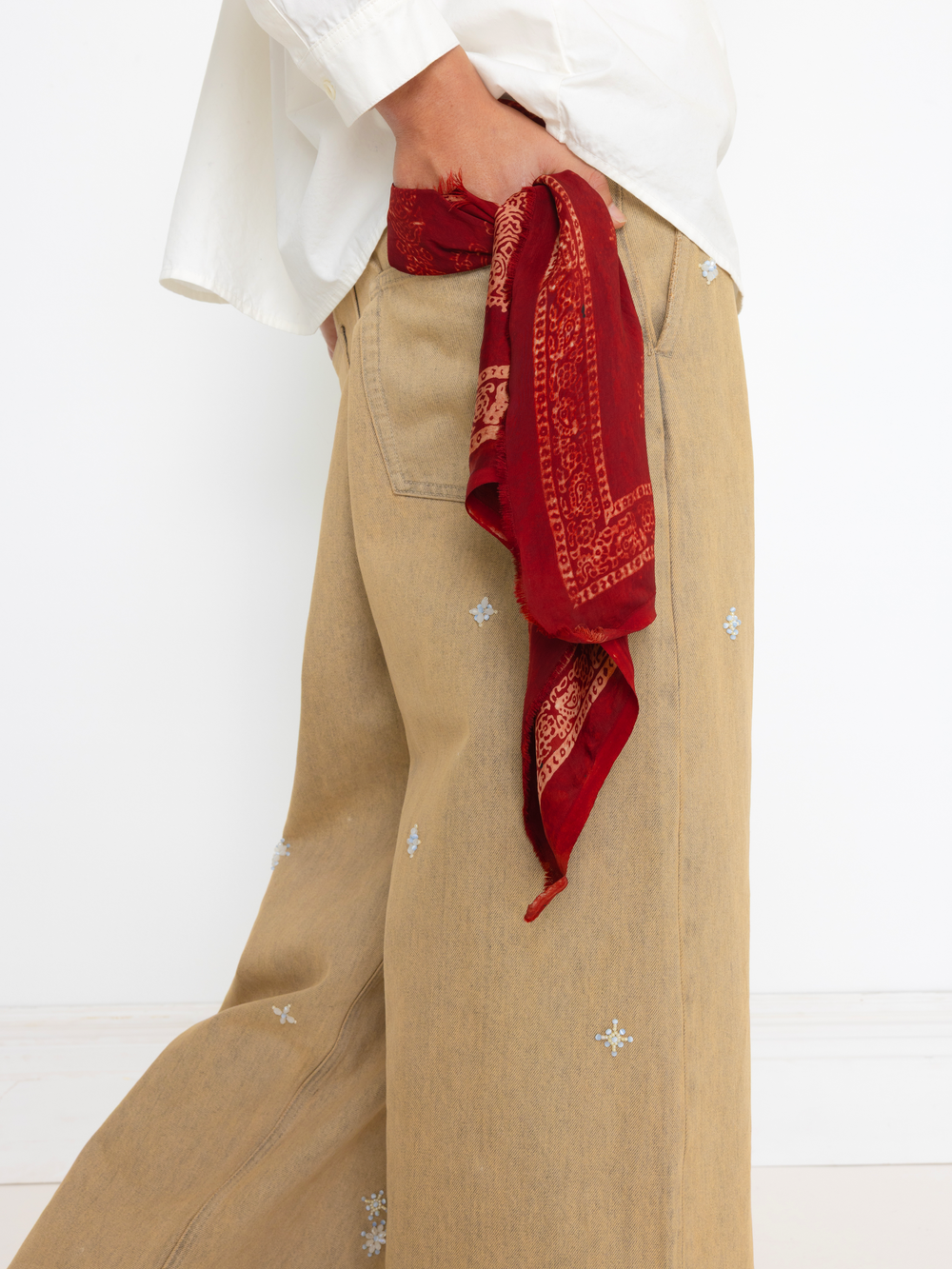 Person wearing beige pants with a red bandana tied around the waist on a white background