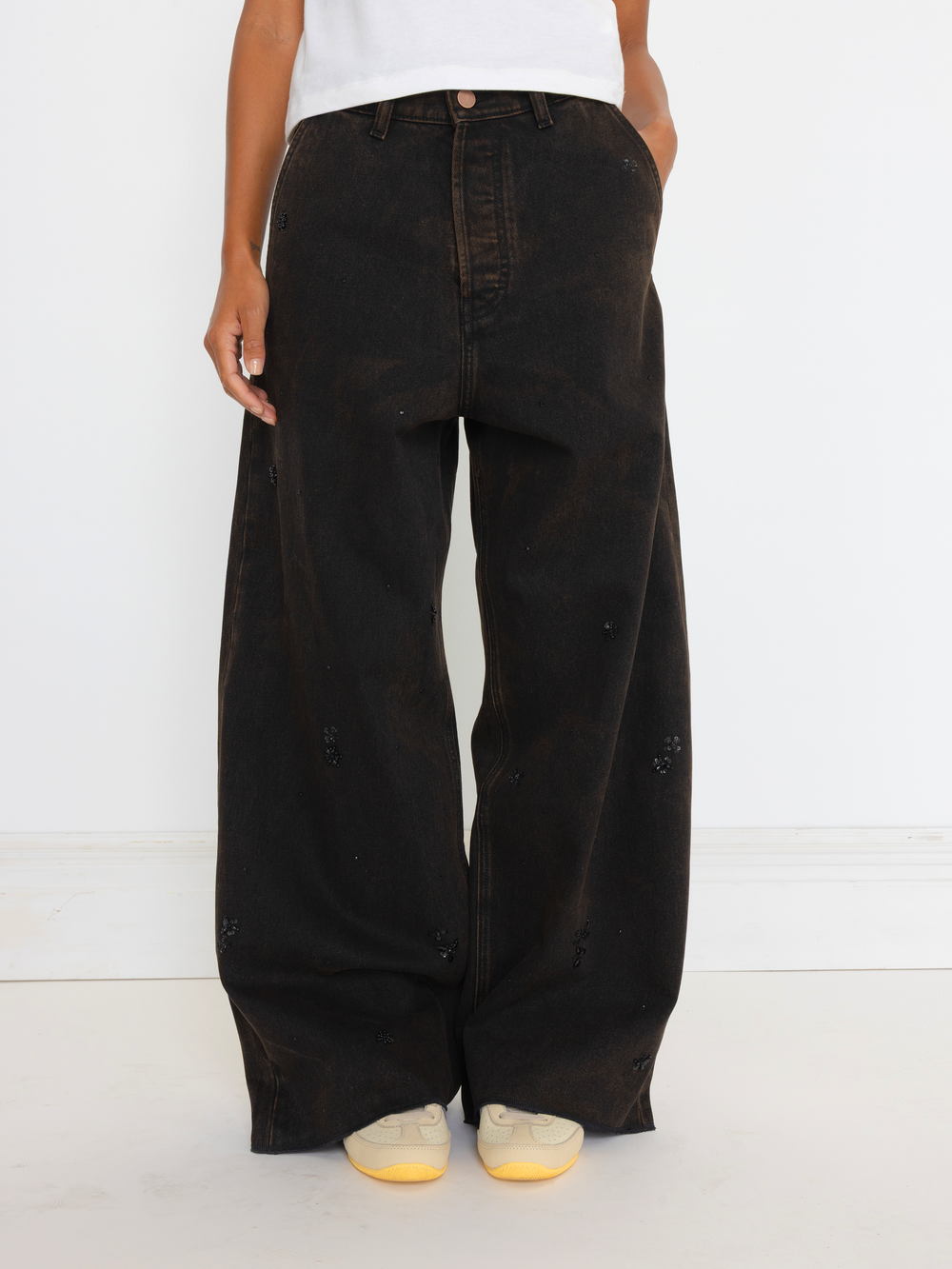 Person wearing black wide-leg jeans on a white background