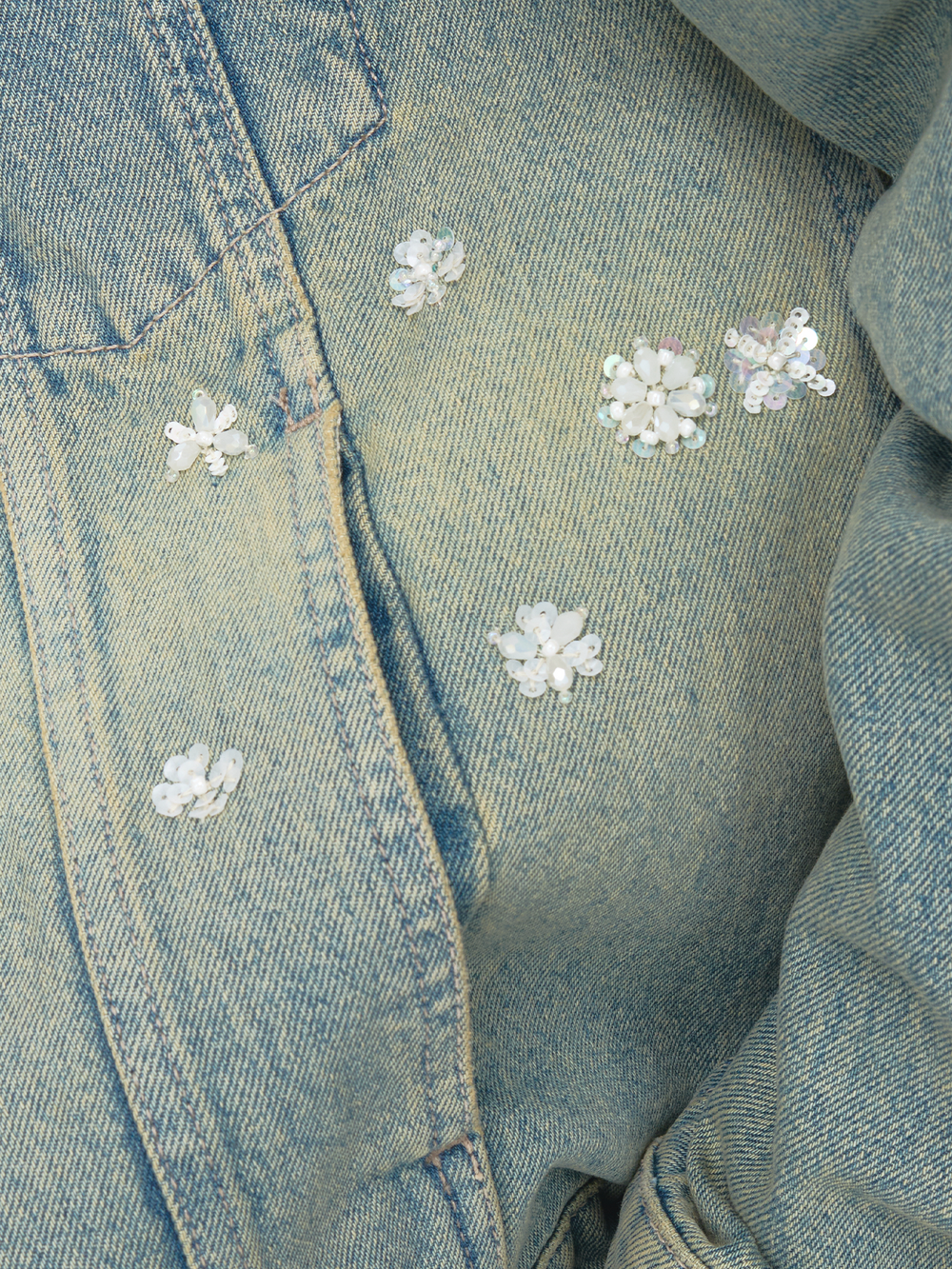Close-up of a denim jacket with floral embellishments.