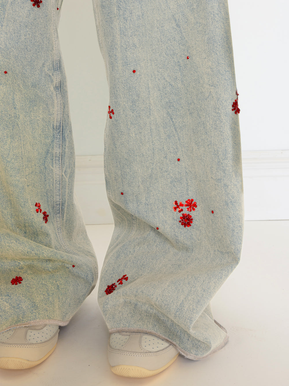 Light blue pants with red floral patterns worn by a person on a white background