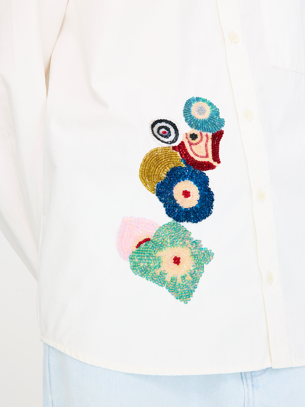 Close-up of a colorful floral beaded design on a white garment.