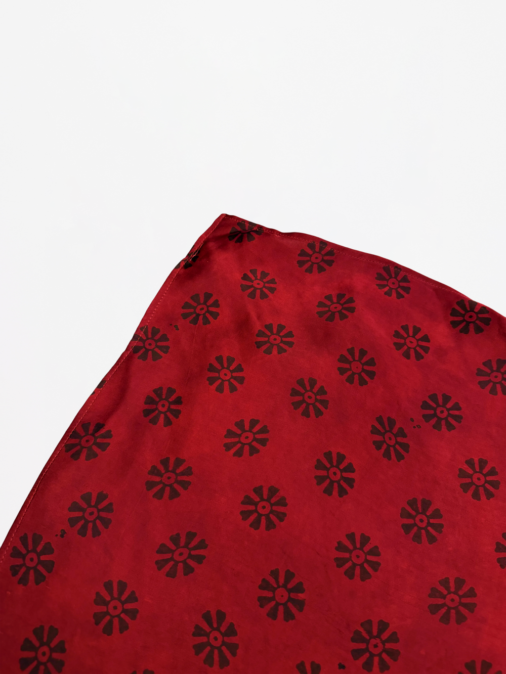 Red fabric with black floral patterns on a white background