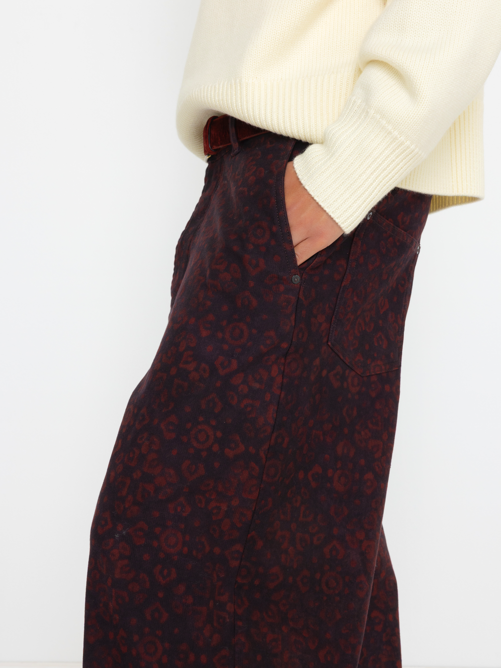 Dark patterned skirt with a white sweater on a light background