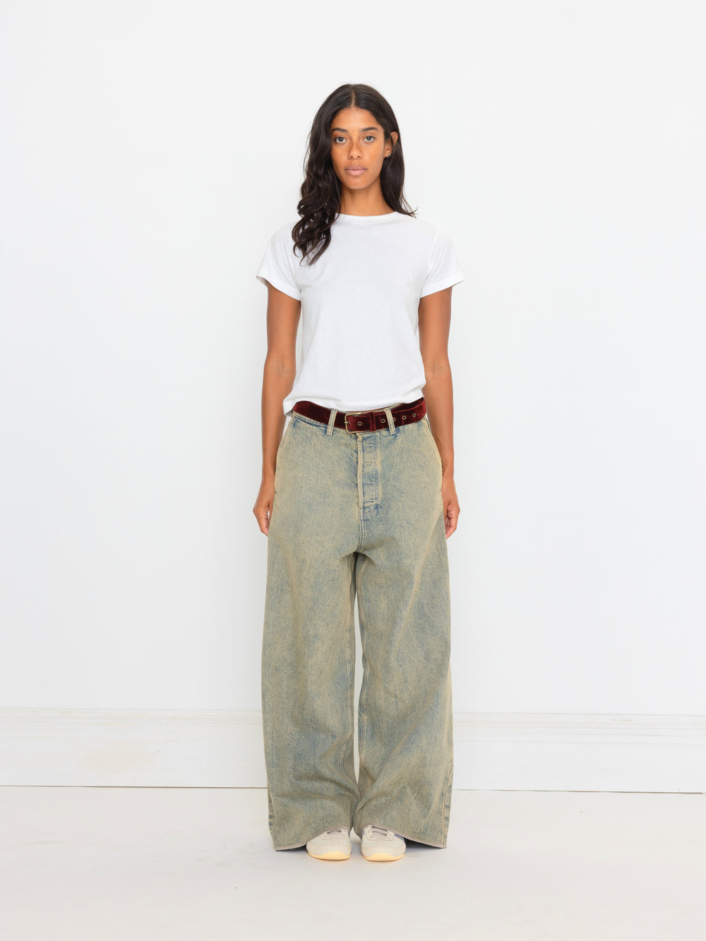 Woman wearing a white t-shirt and light green wide-leg jeans on a white background