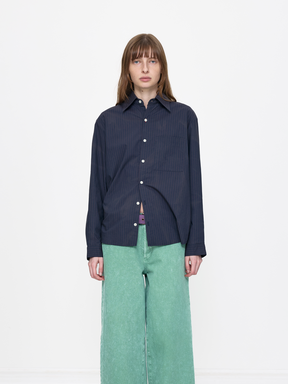 Person wearing a dark blue button-up shirt and green pants on a white background