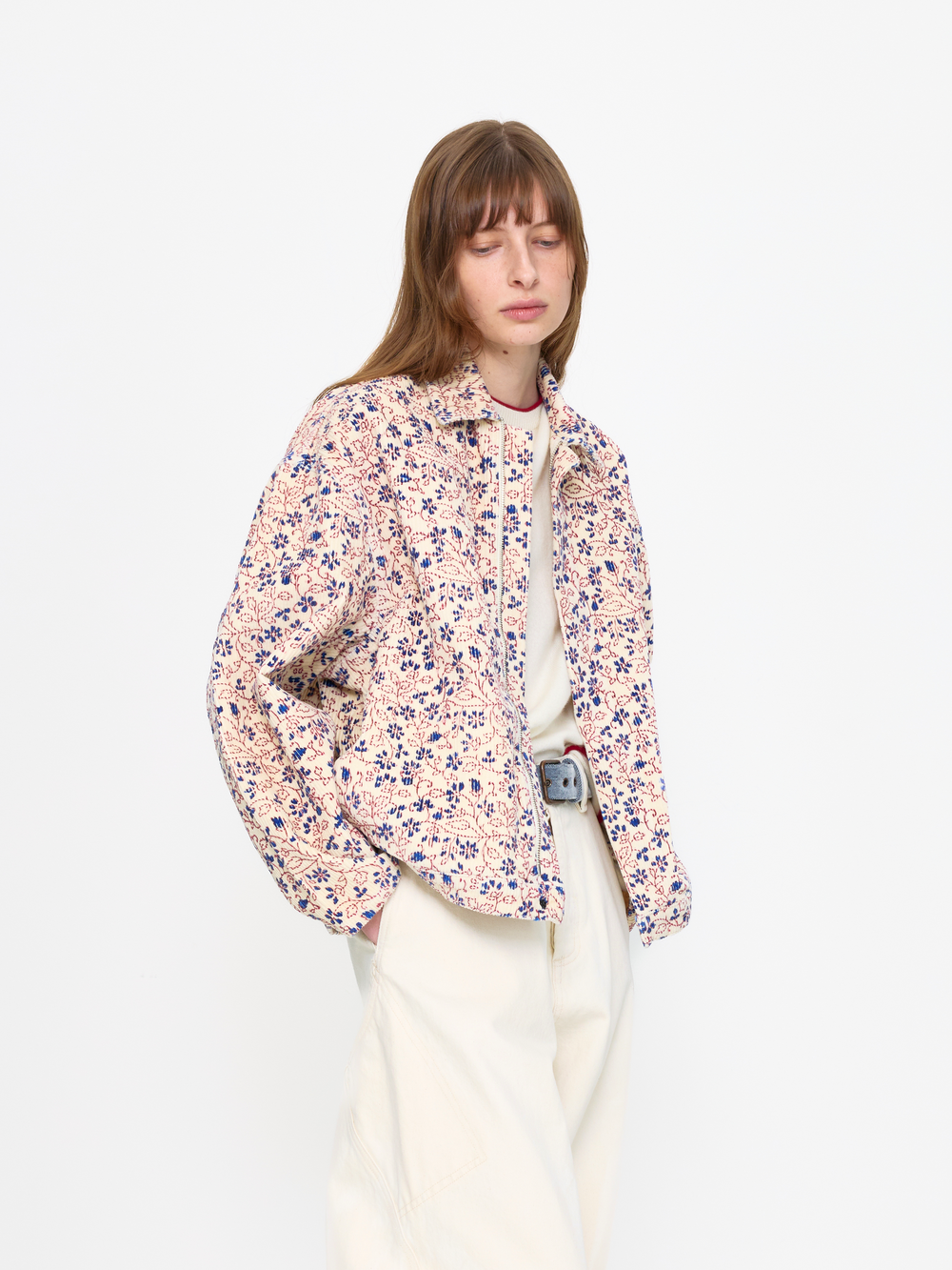 Woman wearing a floral blouse and white pants on a white background