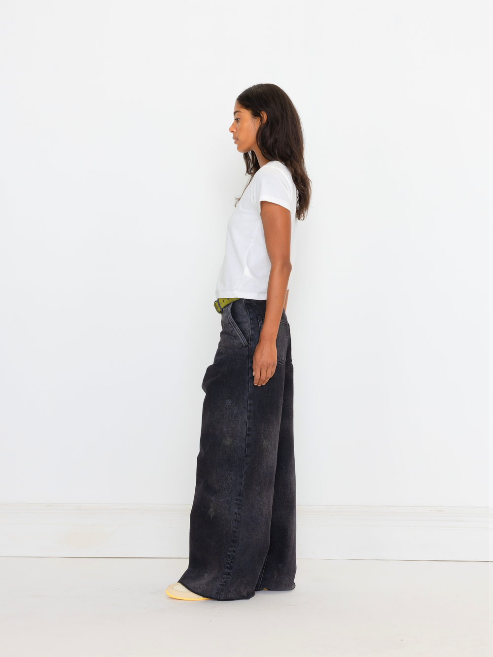 Person wearing a white t-shirt and dark wide-leg pants on a white background