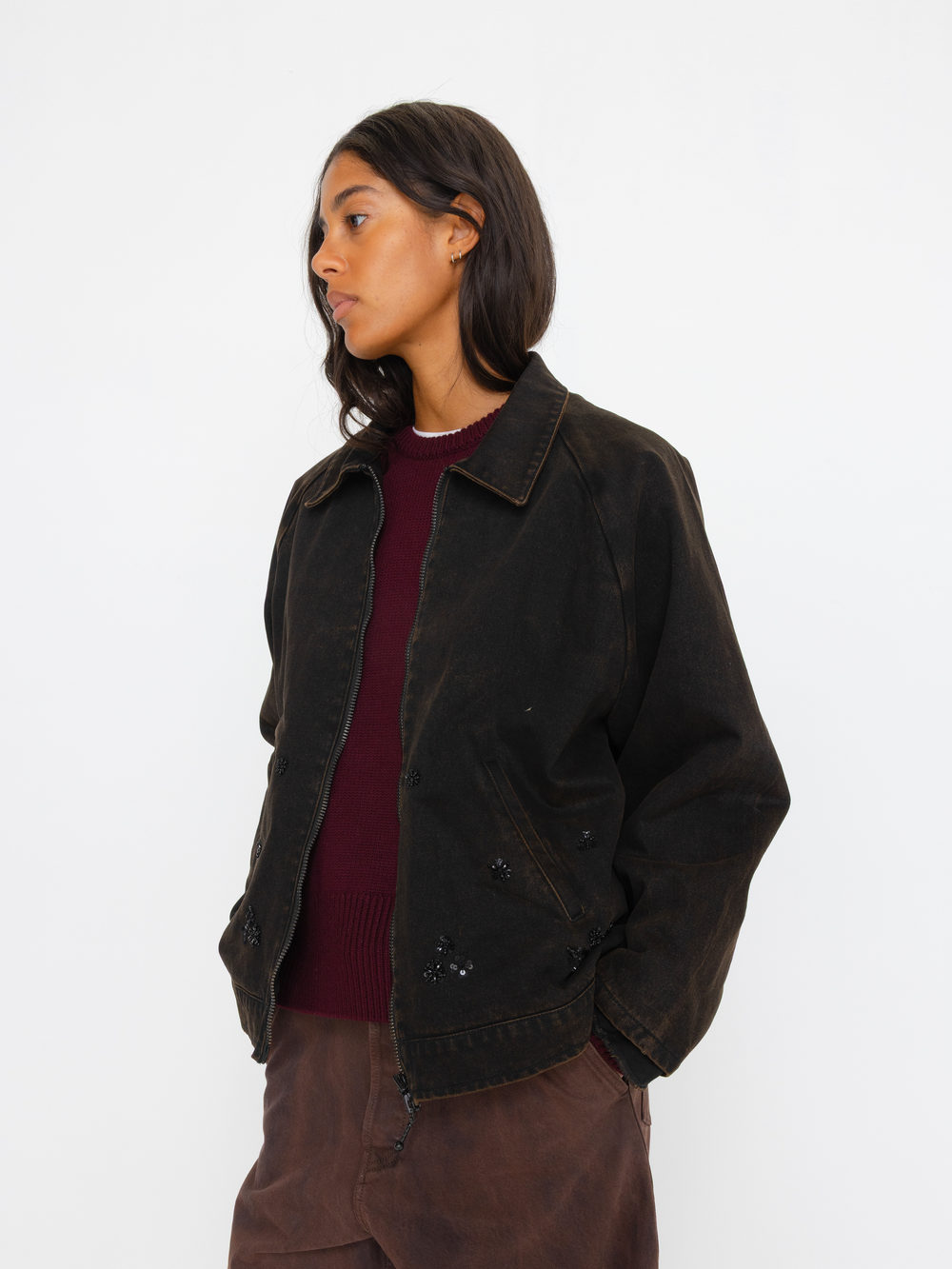 Person wearing a dark brown jacket and maroon shirt on a white background