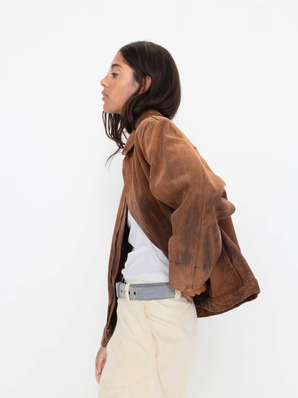 Person wearing a brown jacket over a white shirt on a white background