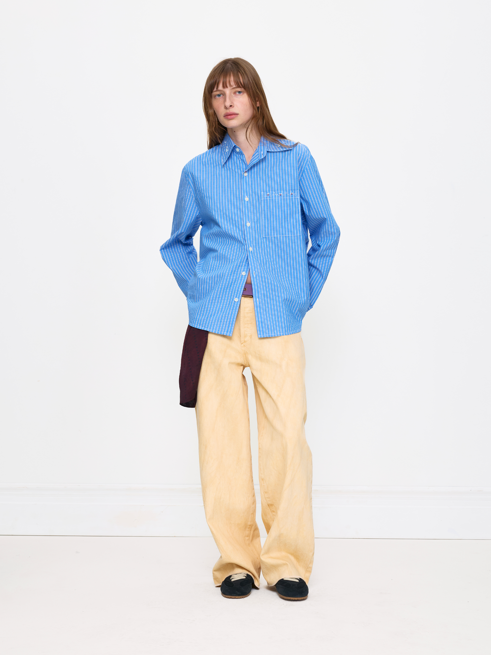 Person wearing a blue checkered shirt and beige pants on a white background