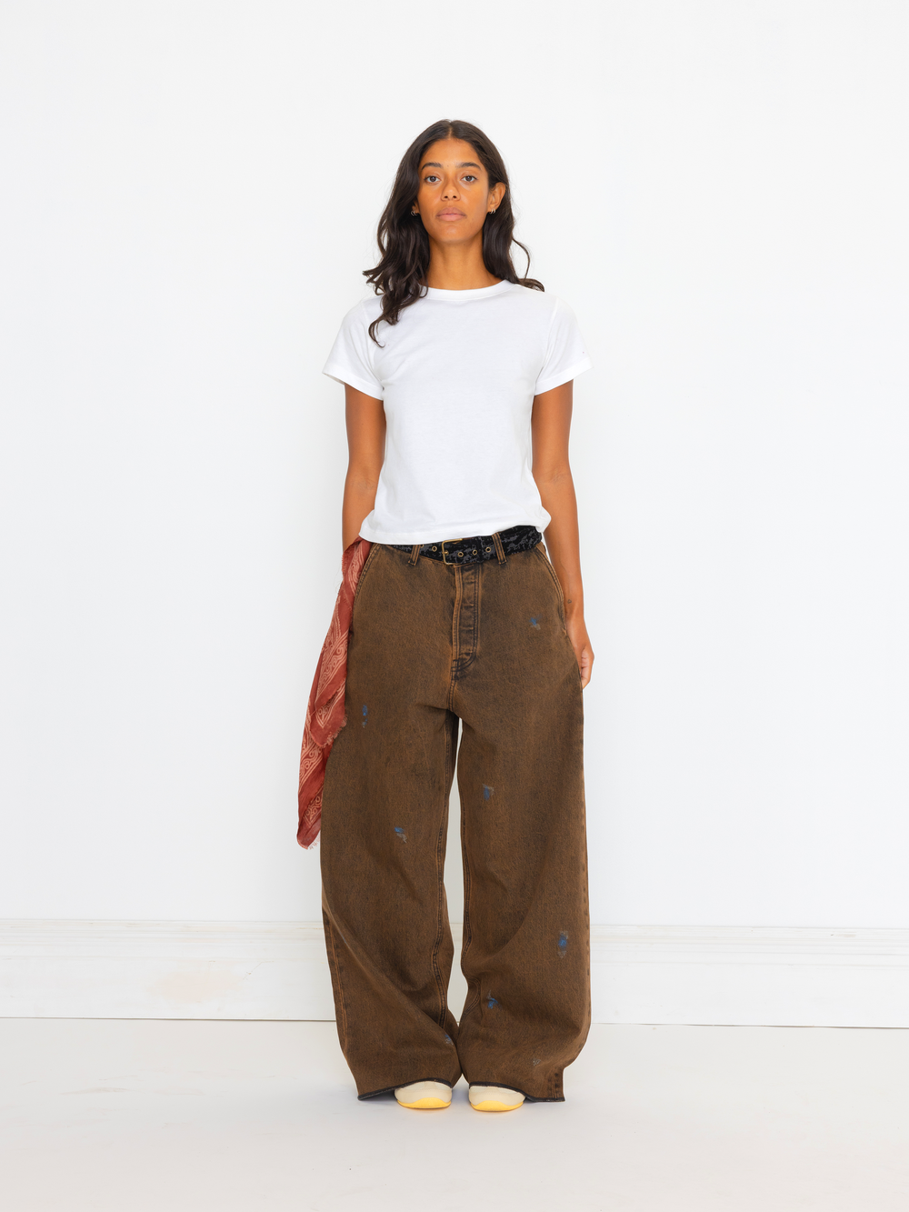 Person wearing a white t-shirt and brown pants on a white background