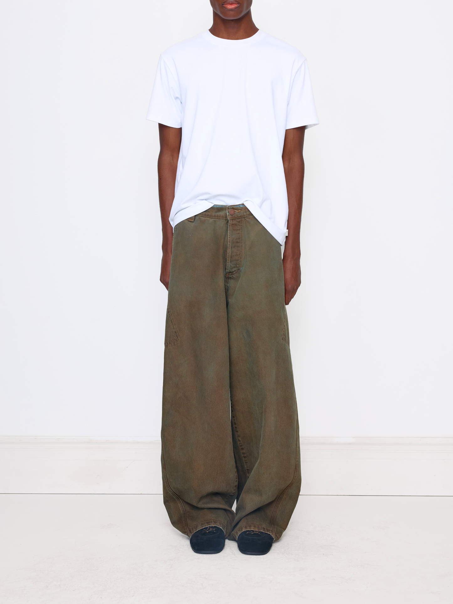 A model wearing a white crewneck t-shirt and wide-leg olive green cargo pants, standing against a plain white studio background.