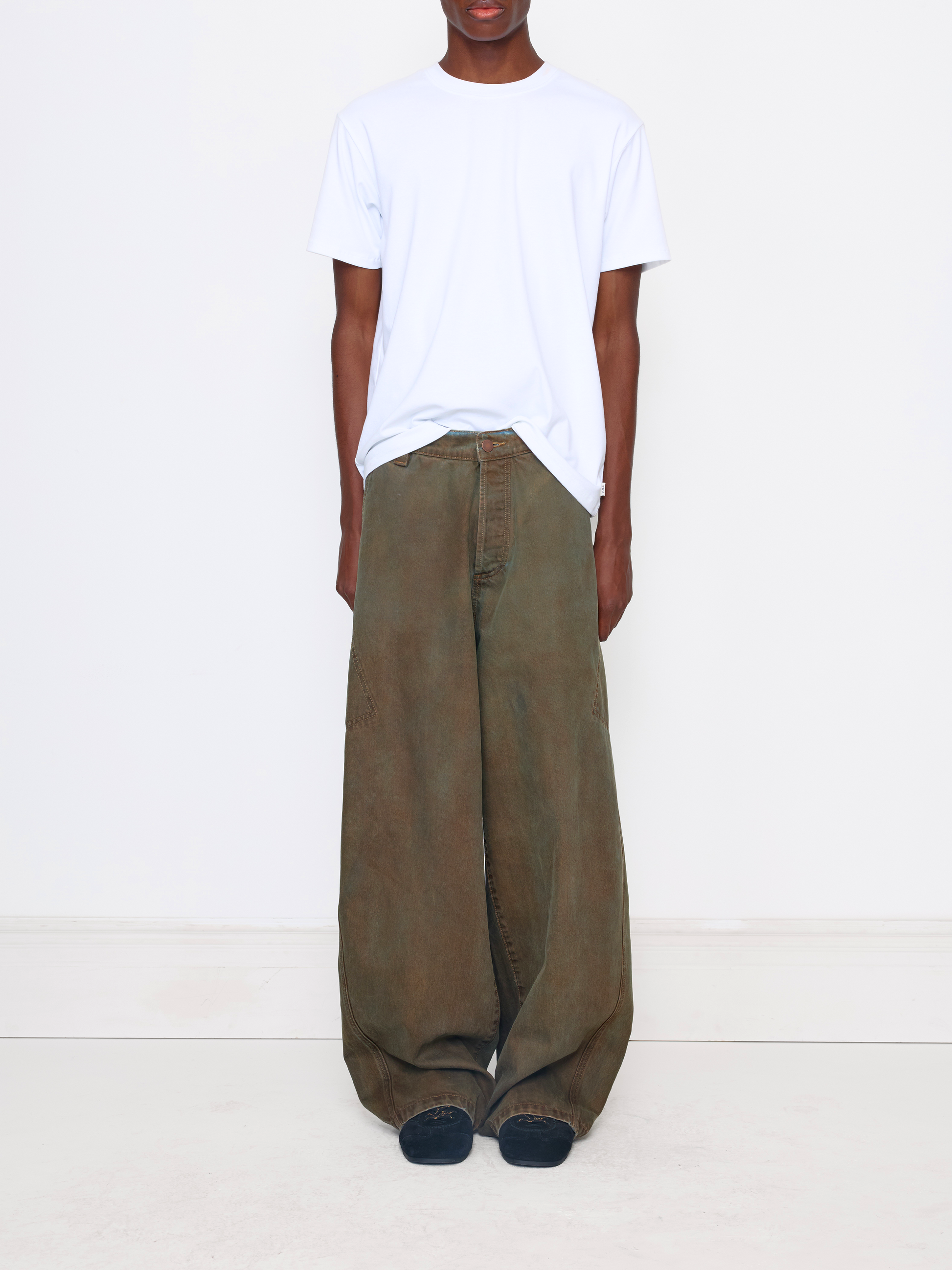 A model wearing a white crewneck t-shirt and wide-leg olive green cargo pants, standing against a plain white studio background.