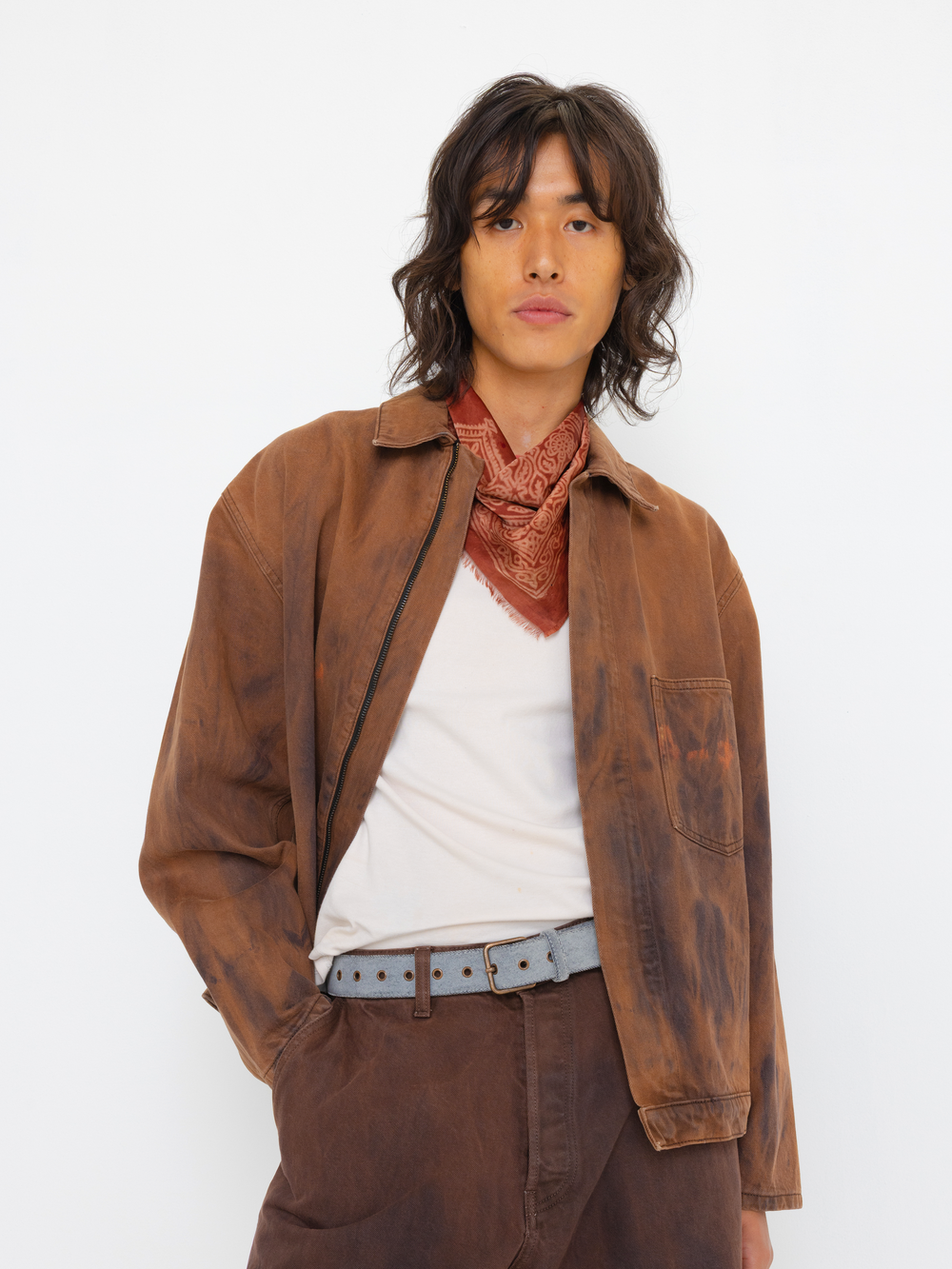 Person wearing a brown jacket and scarf with a white background