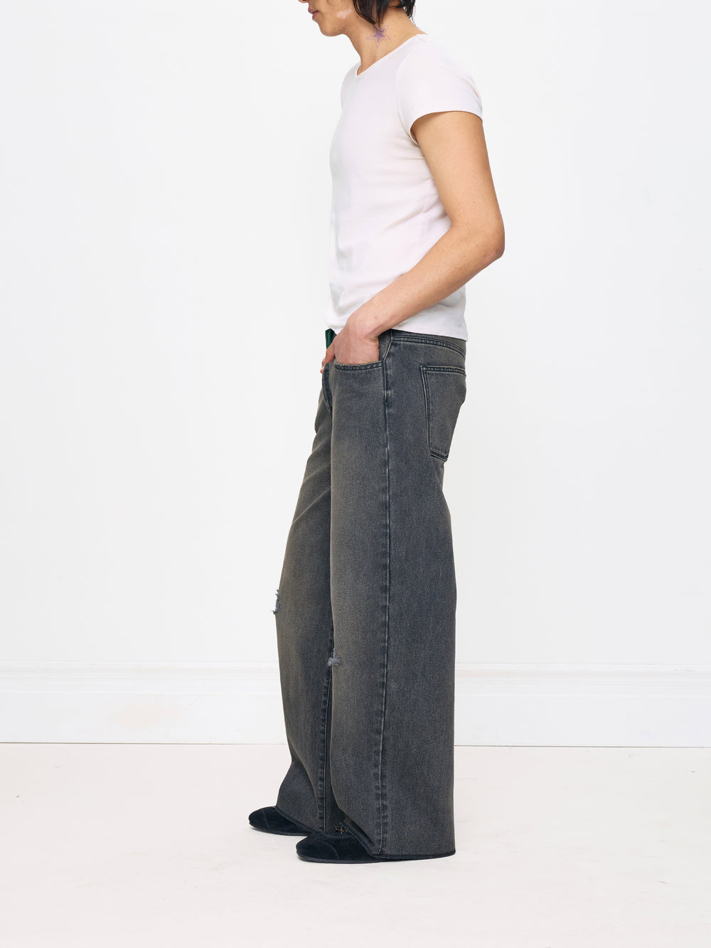 Person wearing a white t-shirt and dark jeans on a white background