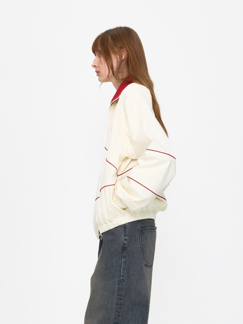 Person wearing a white jacket with red accents and blue jeans on a white background