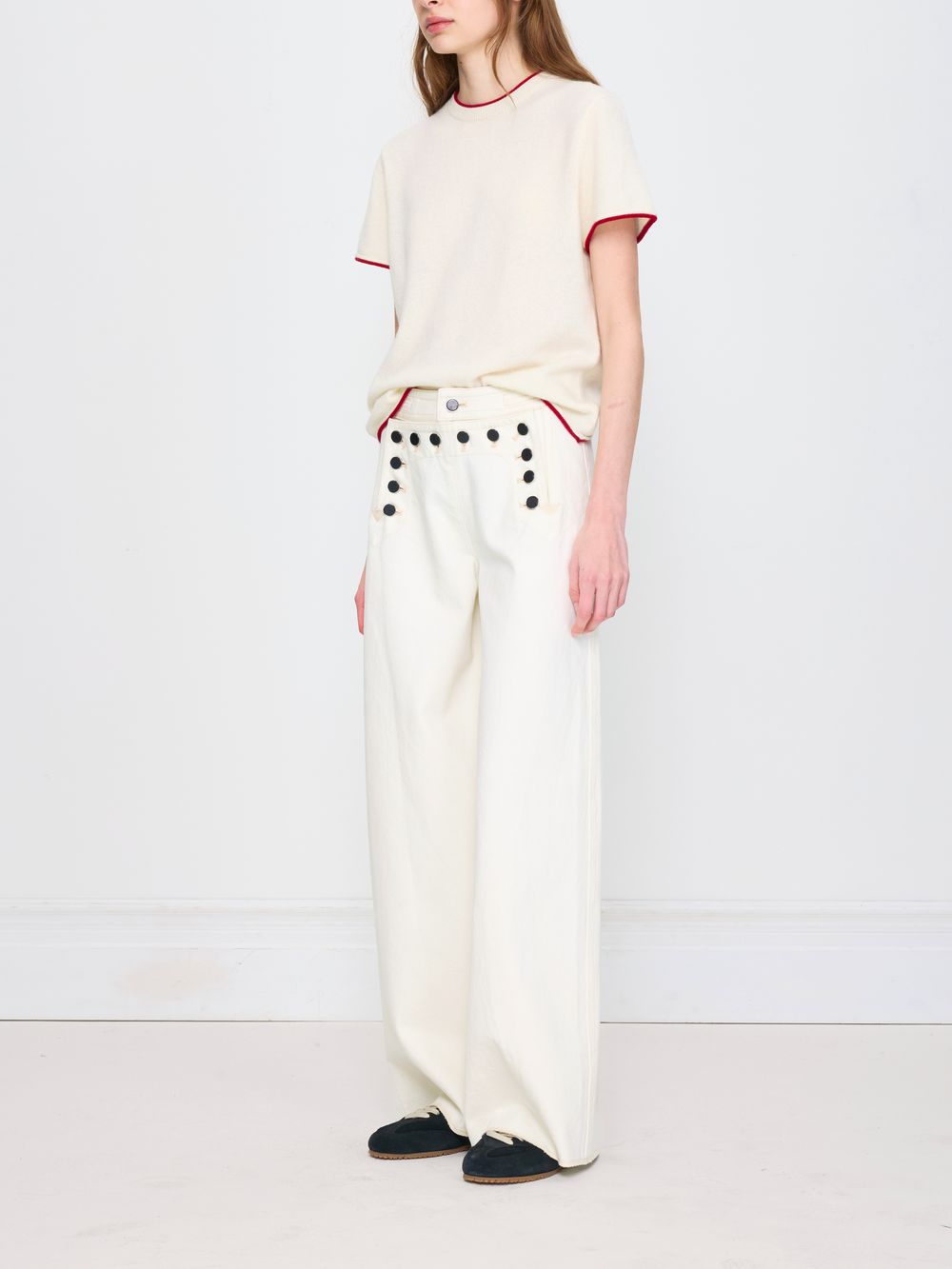 Person wearing a white outfit with red trim on a plain background